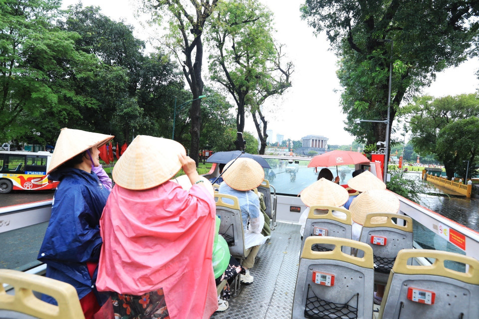 Dù trời có mưa nhưng du khách vẫn háo hức tham quan Hà Nội bằng xe buýt 2 tầng miễn phí. (Ảnh: Tuấn Anh/TTXVN)