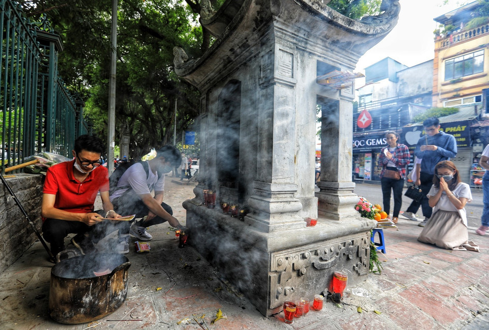 Trước cửa Văn Miếu người thì đốt vàng mã, người thì khấn vái cầu may. (Ảnh: Thành Đạt/TTXVN)