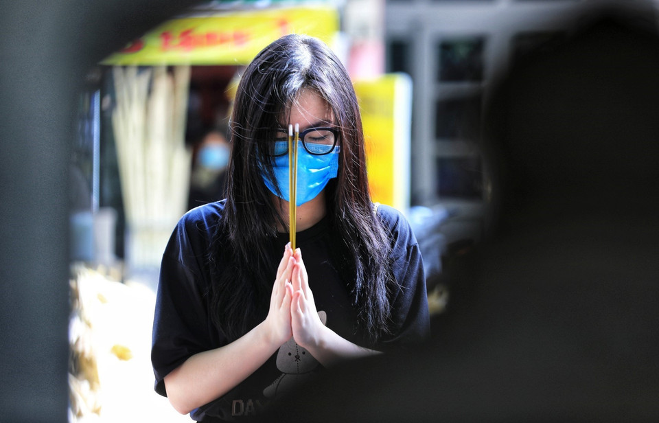 Các sỹ tử tuân thủ đeo khẩu trang đến dâng hương vái vọng bên ngoài cửa Văn Miếu-Quốc Tử Giám. (Ảnh: Thành Đạt/TTXVN)