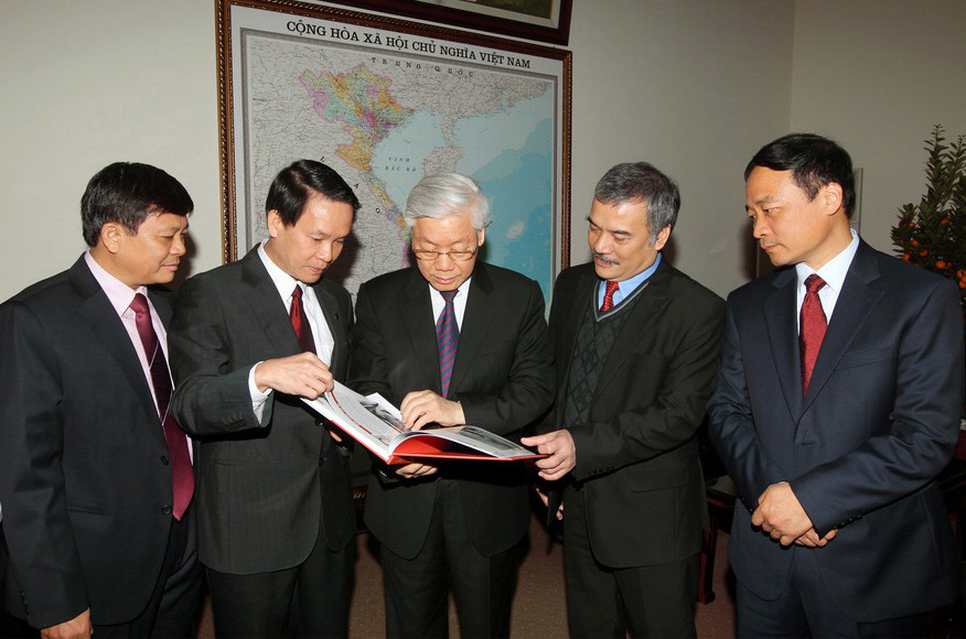 Tổng Bí thư Nguyễn Phú Trọng và các đồng chí lãnh đạo TTXVN xem các ấn phẩm mới được phát hành của TTXVN. (Ảnh: Trí Dũng/TTXVN)