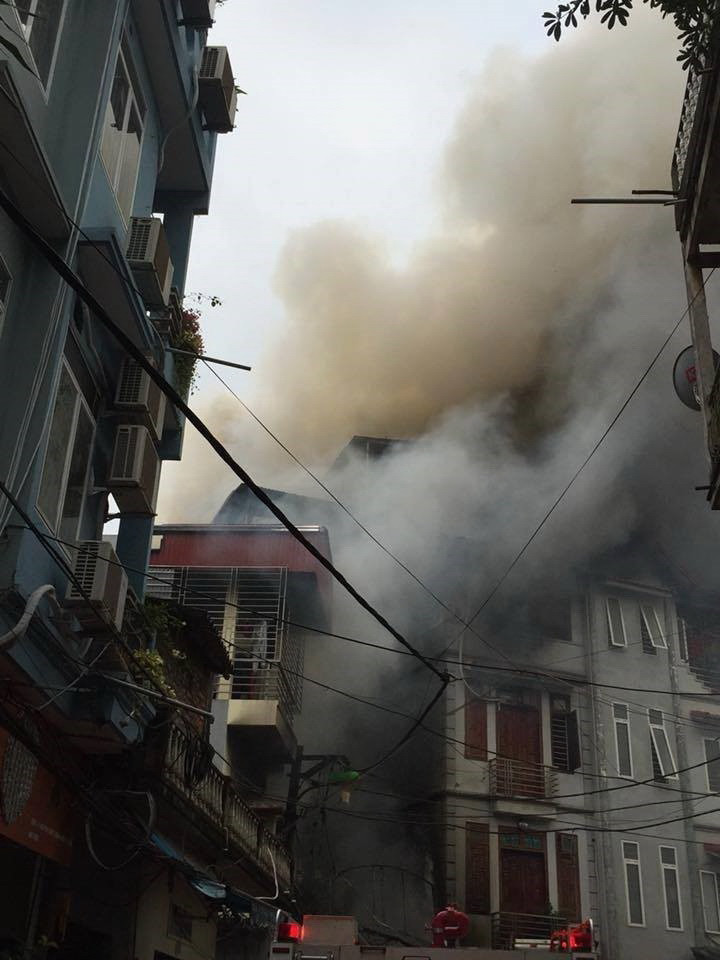 Ngọn lửa bốc lên từ quán karaoke 75 phố Nguyễn Khiết, sau đó lan sang các nhà xung quanh với cột khói bốc cao. (Ảnh: TTXVN)