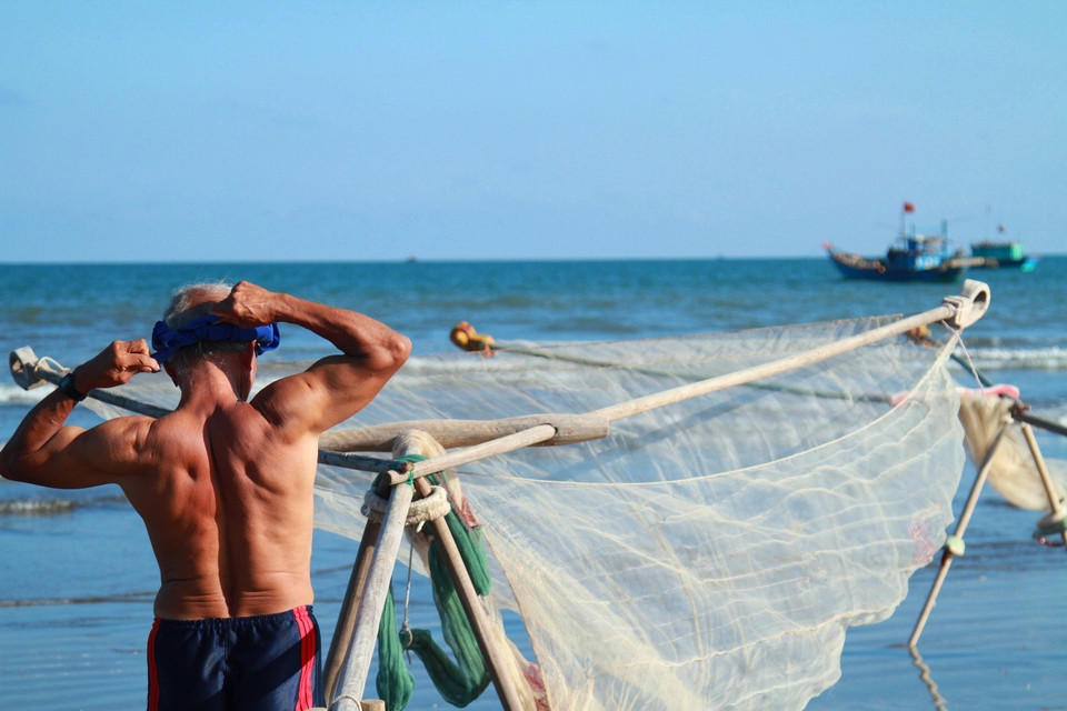 Hơn 40 năm gắn bó với biển, tới giờ đã ngoại lục tuần mà ông Nương vẫn khiến thanh niên trai làng phải ngưỡng mộ vì cơ bắp cuồn cuộn tráng kiện và rắn rỏi. (Ảnh: Xuân Mai/Vietnam+)