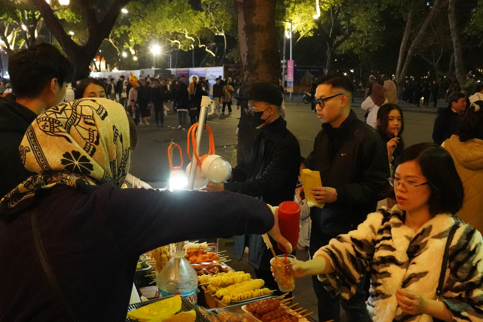 Các quầy hàng bán đồ ăn cũng tất bật chuẩn bị tiếp đón khách hàng trong đêm 30 Tết. (Ảnh: Việt Anh/Vietnam+)