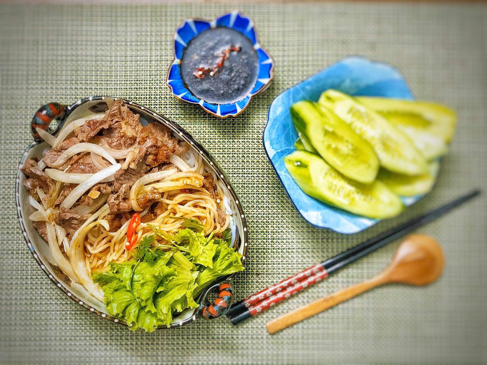 Phi thơm tỏi để xào bò với hành tây cùng chút tiêu rồi trộn bún với hỗn hợp nước sốt ở trên, nêm nếm vừa miệng. Thêm giá, dưa chuột, hành phi thơm, lạc rang tùy theo khẩu vị. (Ảnh: Đậu Đậu/Vietnam+)