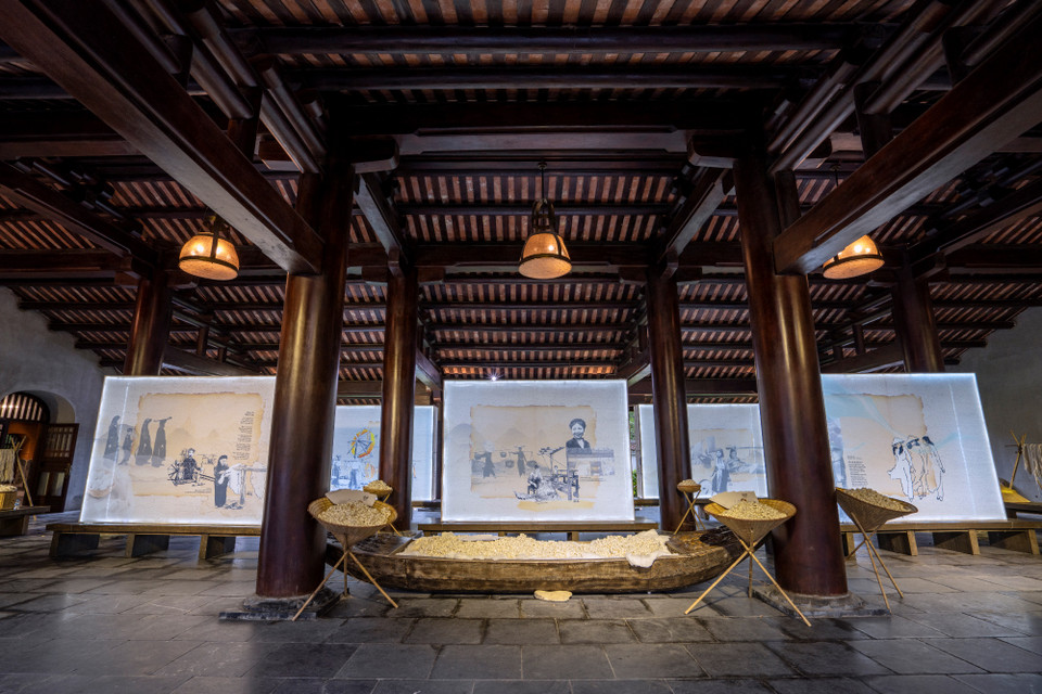 Một quy trình hoàn toàn thủ công được thể hiện qua từng kén tằm, cuộn tơ, thước vải,… bày biện trên chiếc nón lá, con thuyền gỗ hay khung tre bình dị, xen kẽ những bức tranh lụa về lịch sử áo dài qua hàng trăm năm. (Ảnh: CTV/Vietnam+)