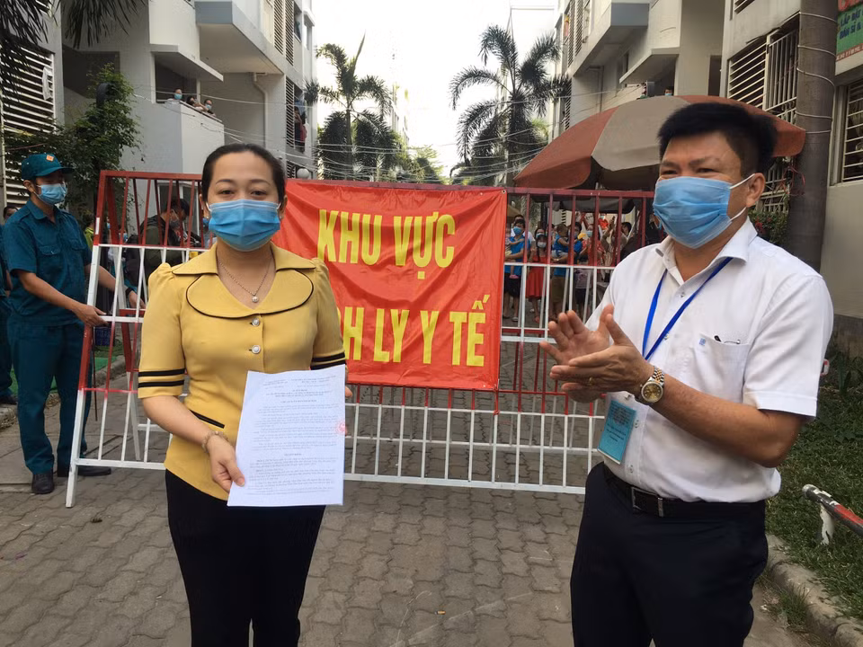 Lãnh đạo Ủy ban nhân dân phường Vĩnh Phú công bố quyết định dỡ bỏ phong tỏa khu C2, Khu dân cư Ehome4. (Ảnh: Văn Hướng/TTXVN)