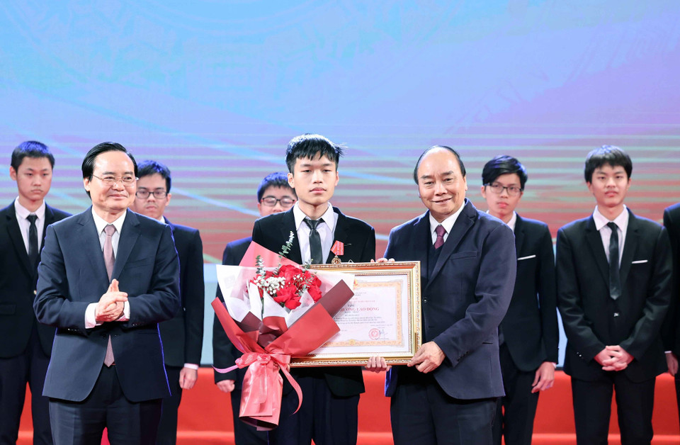 Thủ tướng Nguyễn Xuân Phúc, Chủ tịch Hội đồng Thi đua-Khen thưởng Trung ương trao tặng Huân chương Lao động hạng Nhất cho em Bùi Hồng Đức, học sinh lớp 12, Trường Trung học phổ thông Chuyên Khoa học Tự nhiên, Trường Đại học Tự nhiên, Đại học Quốc gia Hà Nội. (Ảnh: Thống Nhất/TTXVN)