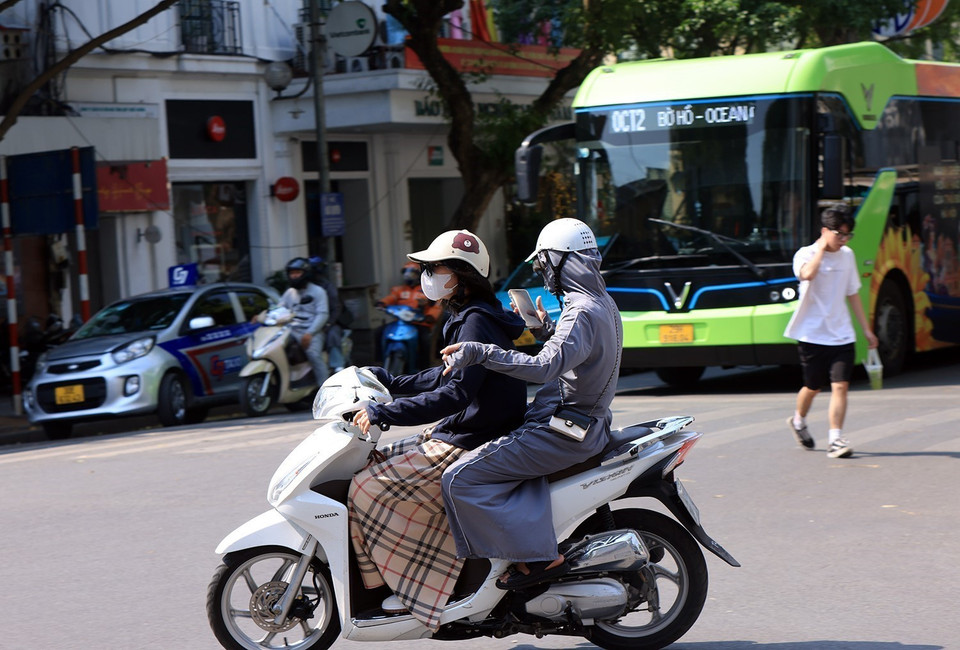 Người dân ra đường dưới cái nóng gay gắt bắt buộc che kín mít, bảo vệ sức khỏe bản thân. (Ảnh: Tuấn Anh/TTXVN)