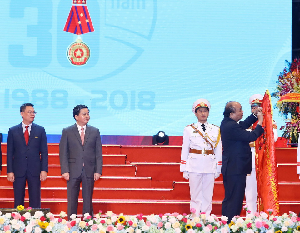 Thủ tướng Nguyễn Xuân Phúc gắn Huân chương Lao động hạng Nhất lên lá cờ truyền thống của Ngân hàng thương mại cổ phần Công Thương Việt Nam (VietinBank). (Ảnh: Thống Nhất/TTXVN)
