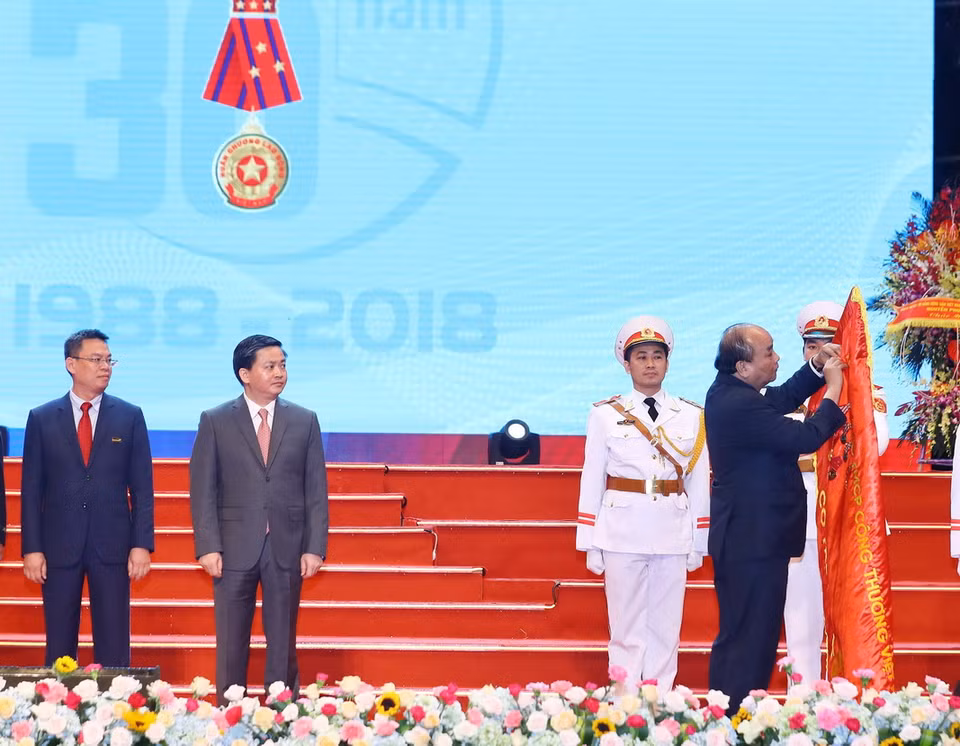 Thủ tướng Nguyễn Xuân Phúc gắn Huân chương Lao động hạng Nhất lên lá cờ truyền thống của Ngân hàng thương mại cổ phần Công Thương Việt Nam (VietinBank). (Ảnh: Thống Nhất/TTXVN)