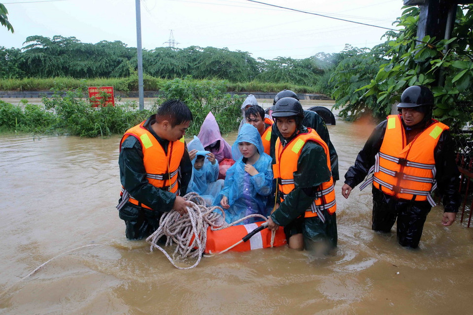 Lực lượng công an, dân quân giúp dân phường Hòa Khánh Nam, quận Liên Chiểu di dời ra khỏi vùng bị ngập nước trên các bè phao. (Ảnh: Trần Lê Lâm/TTXVN)