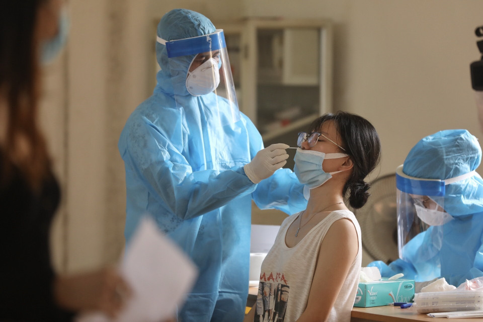 Nhân viên Trung tâm y tế quận Hoàn Kiếm lấy mẫu xét nghiệm COVID-19 cho các trường hợp trở về từ Thành phố Hồ Chí Minh, chiều 10/7. (Ảnh: Minh Quyết/TTXVN)