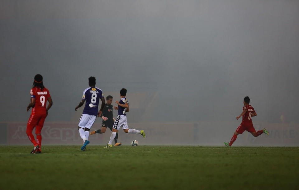 Hai đội thi đấu trong màn khói mù mịt bởi cổ động viên Hải Phòng đốt pháo sáng trên khán đài. (Ảnh: Trọng Đạt/TTXVN)