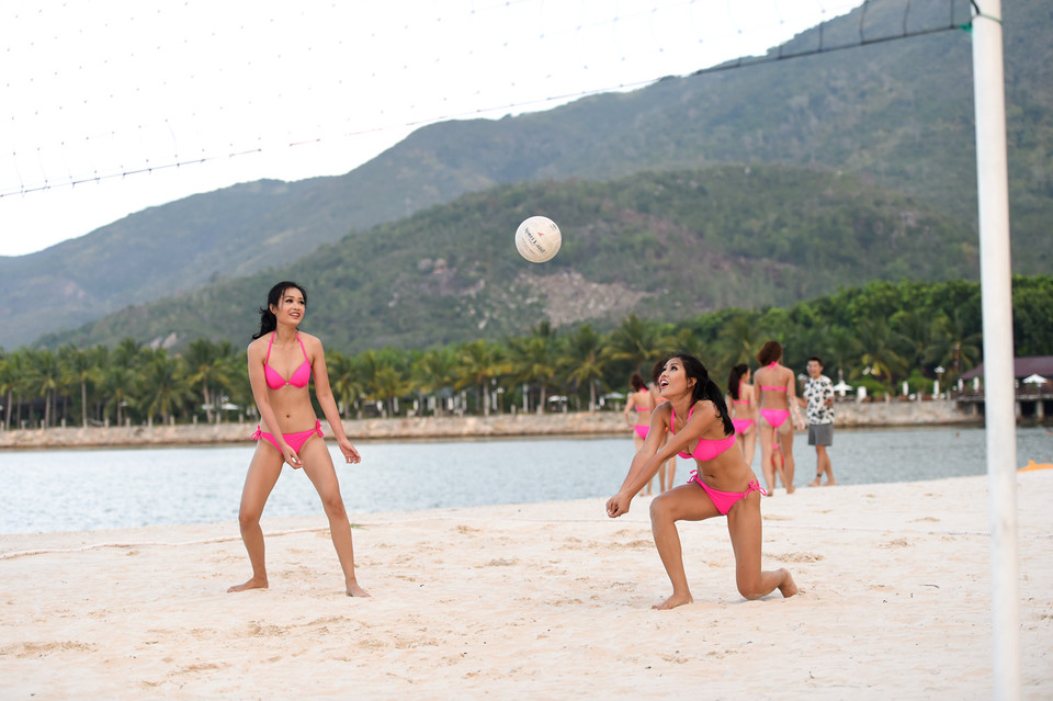 Hình ảnh các người đẹp trong bộ bikini hồng khoe vòng eo thon gọn và săn chắc tập luyện làm nổi bật một góc bãi biển.