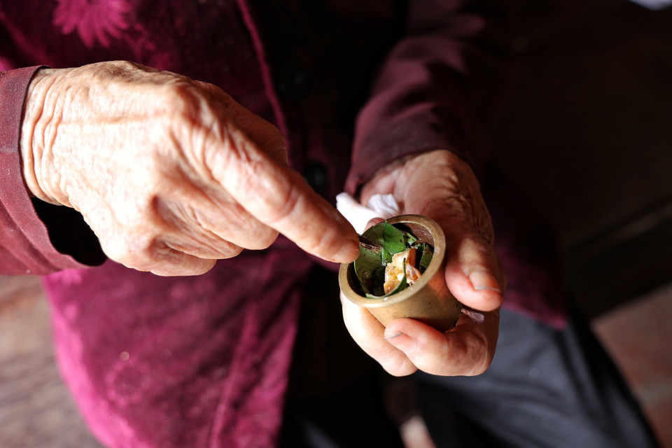 Đây chính xác là cách ăn trầu truyền thống của các cụ ta xưa với chiếc cối đồng nhỏ, dùng tay giã đâm nát lá trầu đã quệt vôi tôi cùng miếng cau bổ tám. (Ảnh: Xuân Mai/Vietnam+)