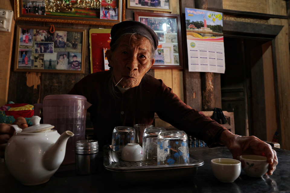 Cụ Hà Thị Cầm năm nay đã 95 tuổi, là một trong những cao niên còn khỏe mạnh của làng nhanh nhẹn rót nước mời khách dù biết tôi chỉ là khách vãng lai. Cũng sống trong căn nhà cổ hàng trăm năm nhưng do con cháu đi làm ăn xa nên hầu như cụ Cầm chỉ ở một mình. (Ảnh: Xuân Mai/Vietnam+)