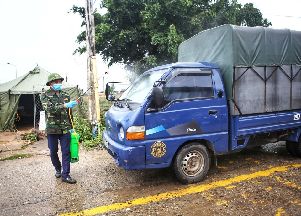 Phun khử khuẩn phương tiện làm nhiệm vụ ra-vào thôn Hạ Lôi. (Ảnh: Danh Lam/TTXVN)