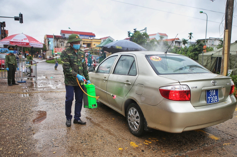 Việc phun khử khuẩn phương tiện ra-vào thôn Hạ Lôi vẫn được thực hiện đúng quy trình. (Ảnh: Danh Lam/TTXVN)