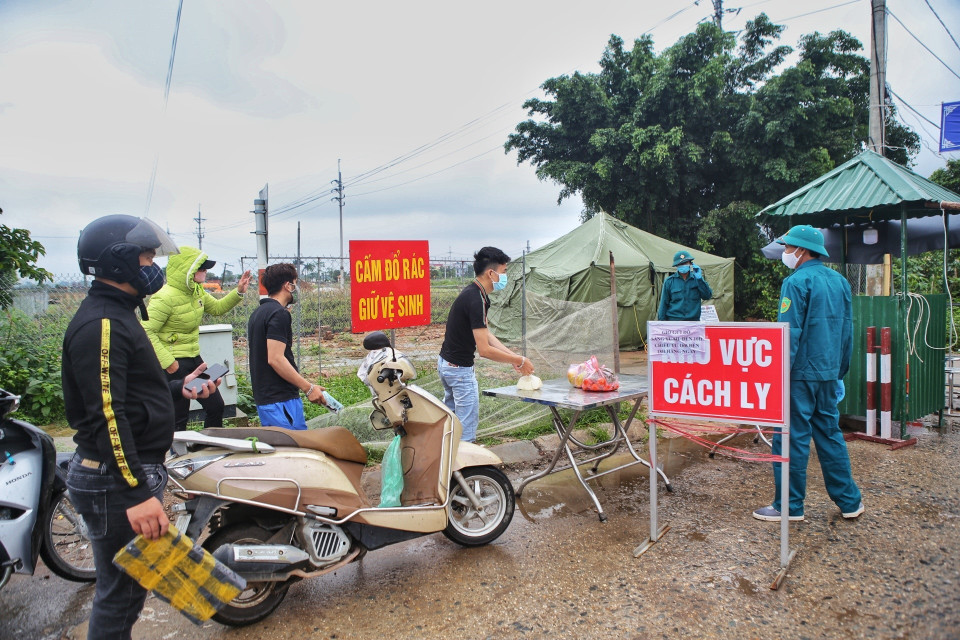 Lực lượng dân quân, tự vệ vận chuyển nhu yếu phẩm vào trong thôn theo đúng quy trình cách ly y tế. (Ảnh: Danh Lam/TTXVN)