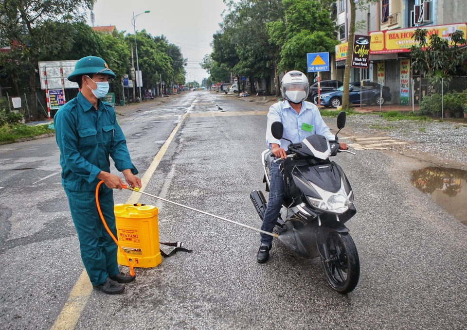 Phun khử khuẩn người và phương tiện có nhiệm vụ được phép ra-vào thôn Hạ Lôi. (Ảnh: Danh Lam/TTXVN)