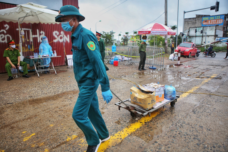 Lực lượng dân quân, tự vệ vận chuyển nhu yếu phẩm vào trong thôn theo đúng quy trình cách ly y tế. (Ảnh: Danh Lam/TTXVN)