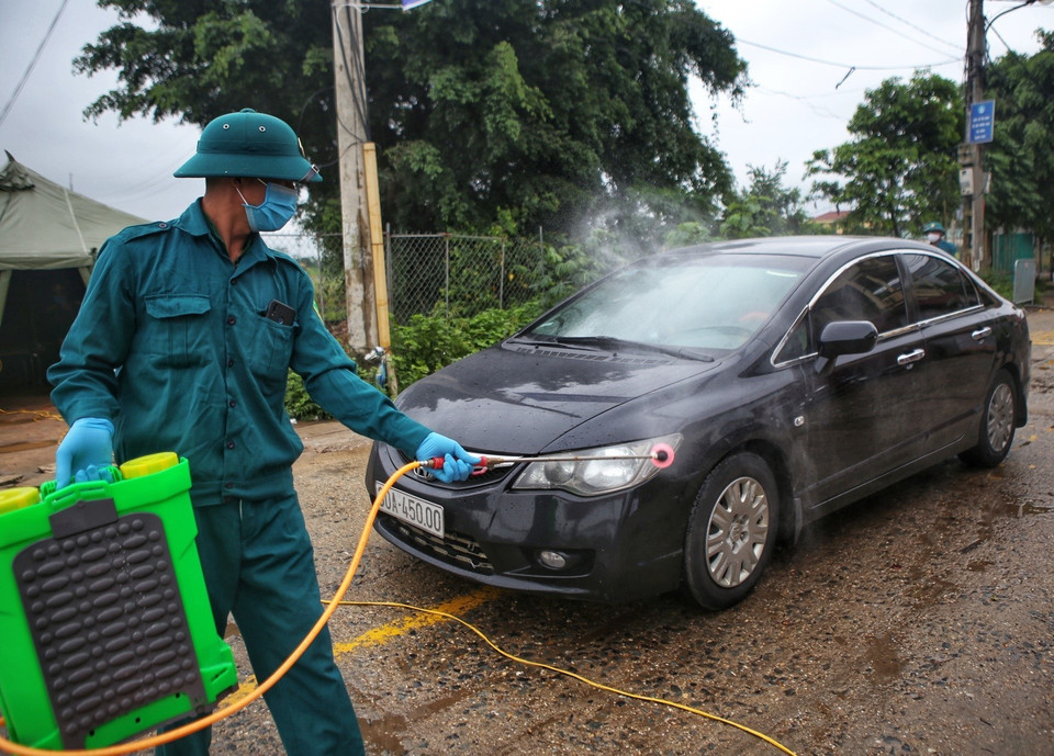 Phun khử khuẩn phương tiện làm nhiệm vụ ra-vào thôn Hạ Lôi. (Ảnh: Danh Lam/TTXVN)