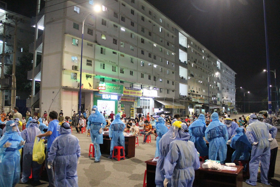 Trung tâm Kiểm soát bệnh tật Bình Dương phối hợp với Trung tâm Y tế thành phố Thủ Dầu Một tiến hành lấy mẫu xét nghiệm xuyên đêm. (Ảnh: Văn Hướng/TTXVN)