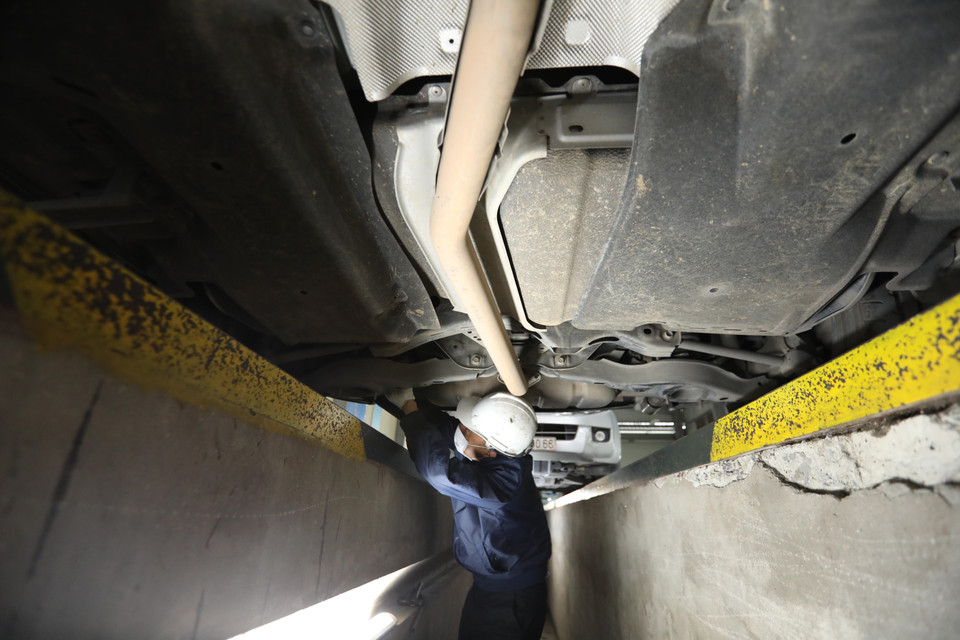 Kiểm định viên Trung tâm đăng kiểm xe cơ giới 2917D tại Long Biên kiểm tra gầm xe. (Ảnh: Hoàng Hiếu/TTXVN)