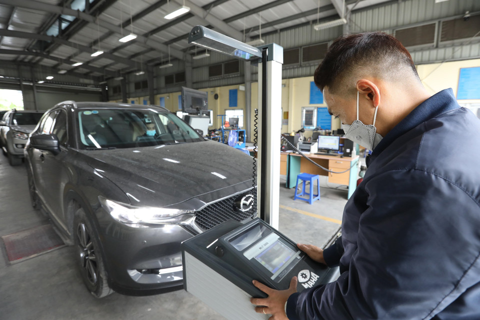 Kiểm định viên Trung tâm đăng kiểm xe cơ giới 2917D tại quận Long Biên đo hệ thống chiếu sáng của xe. (Ảnh: Hoàng Hiếu/TTXVN)