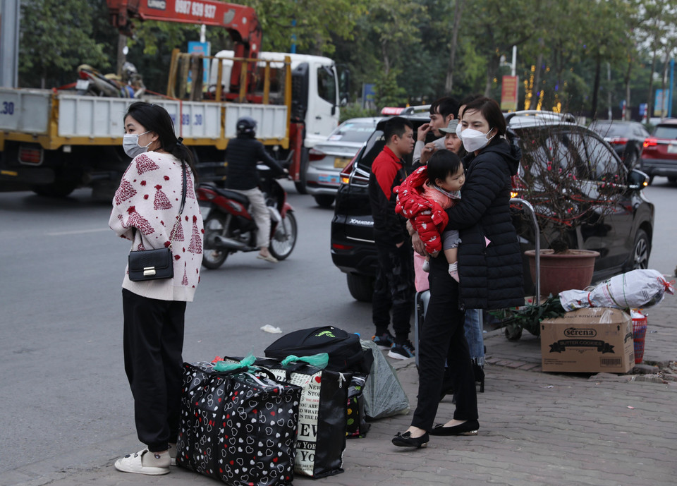 Người dân với túi, đồ đạc... đang chờ đón xe rời Hà Nội. (Ảnh: Hoàng Hiếu/TTXVN)