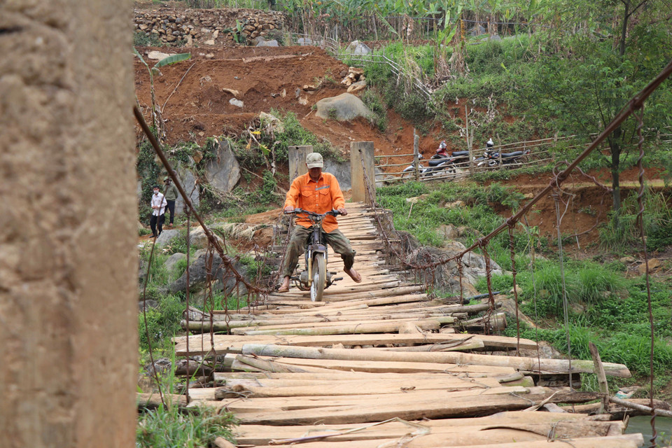 Người dân đi qua một cây cầu treo đã xuống cấp tại xã Chiềng Lương, huyện Mai Sơn. (Ảnh: Hữu Quyết/TTXVN)