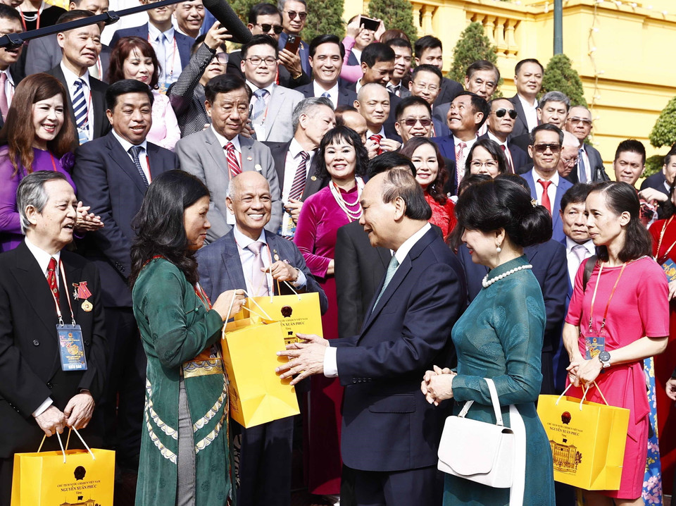 Chủ tịch nước Nguyễn Xuân Phúc tặng quà lưu niệm cho đại biểu kiều bào dự Chương trình Xuân Quê hương 2023, tại Phủ Chủ tịch. (Ảnh: Thống Nhất/TTXVN)