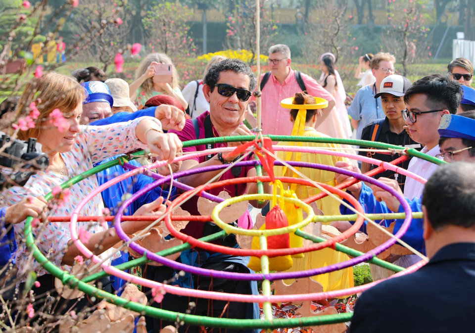 Du khách quốc tế cùng trải nghiệm nghi thức dựng cây nêu ngày Tết. (Ảnh: Thanh Tùng/TTXVN)