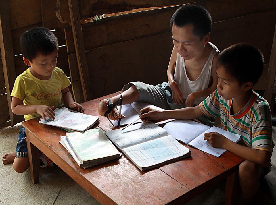 Anh Lê Hồng Sơn (sinh năm 1979, ở xã Phú Gia, huyện Hương Khê, tỉnh Hà Tĩnh) khi sinh ra đã bị liệt cả hai tay, hai chân bị teo và co quặp ra sau. Vượt lên số phận với nghị lực phi thường, anh đã biến đôi chân yếu thành đôi tay 'khéo' để vừa học, vừa đi làm phụ giúp gia đình, đạt thành tích cao trong học tập. Hiện nay, anh là chủ doanh nghiệp gỗ mỹ nghệ Mạnh Dũng. Trong ảnh: Anh Sơn dùng 'đôi chân đặc biệt' dạy con học. (Ảnh: Nguyễn Thủy/TTXVN)