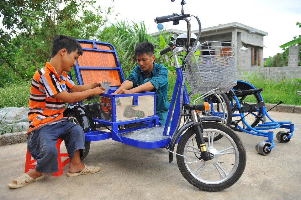 Không may bị dị tật bẩm sinh, khó khăn trong việc đi lại, nhưng anh Lê Văn Lịch (phải) ở xã Trường Yên, huyện Hoa Lư (Ninh Bình) được nhiều người biết đến với ý chí, nghị lực vươn lên trong cuộc sống, là điển hình làm kinh tế ở địa phương nhờ việc làm xe lăn điện cho người khuyết tật, tạo việc làm cho những người khuyết tật khác. (Ảnh: Minh Đức/TTXVN)