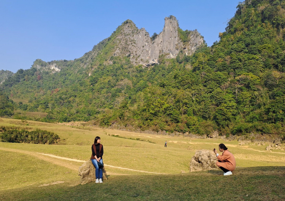 Du khách thích thú chụp ảnh bên bãi cỏ của thung lũng Núi mắt thần. (Ảnh: Quốc Đạt/TTXVN)