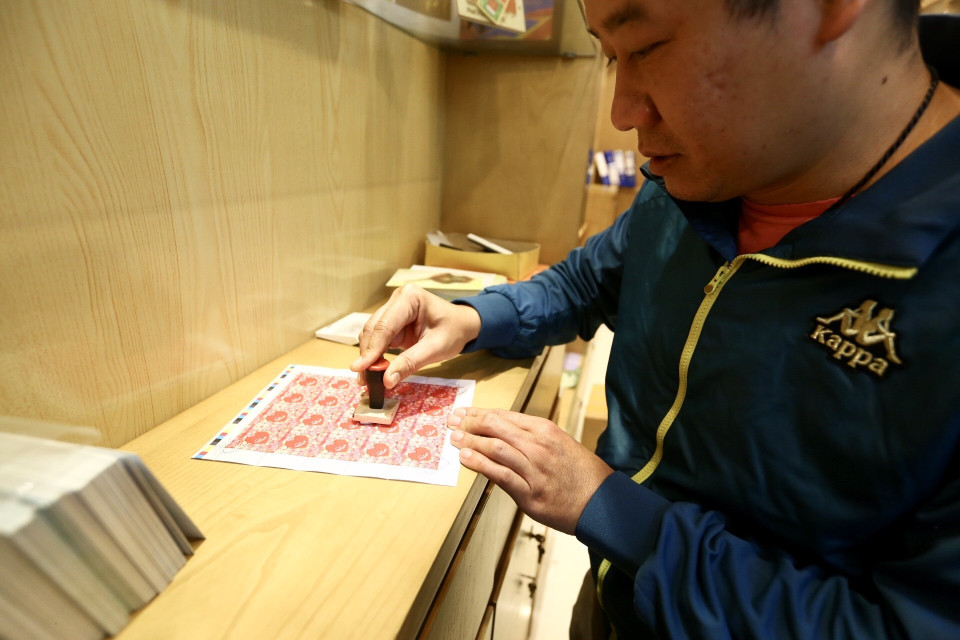 Anh Đào Tuấn Anh (Hà Nội) chọn mua, sưu tầm bộ 'Tem tình yêu' mới được phát hành. (Ảnh: Minh Quyết/TTXVN)