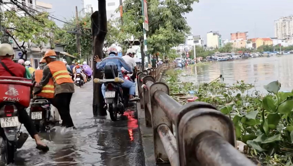 Người dân vất vả di chuyển giữa nước ngập trên đường Trần Xuân Soạn, quận 7. (Ảnh: Thanh Vũ/TTXVN)