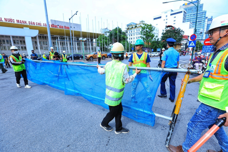 Thanh tra giao thông và công nhân dựng rào chắn phân luồng đoạn đường Trần Hưng Đạo. (Ảnh: Tuấn Anh/TTXVN)