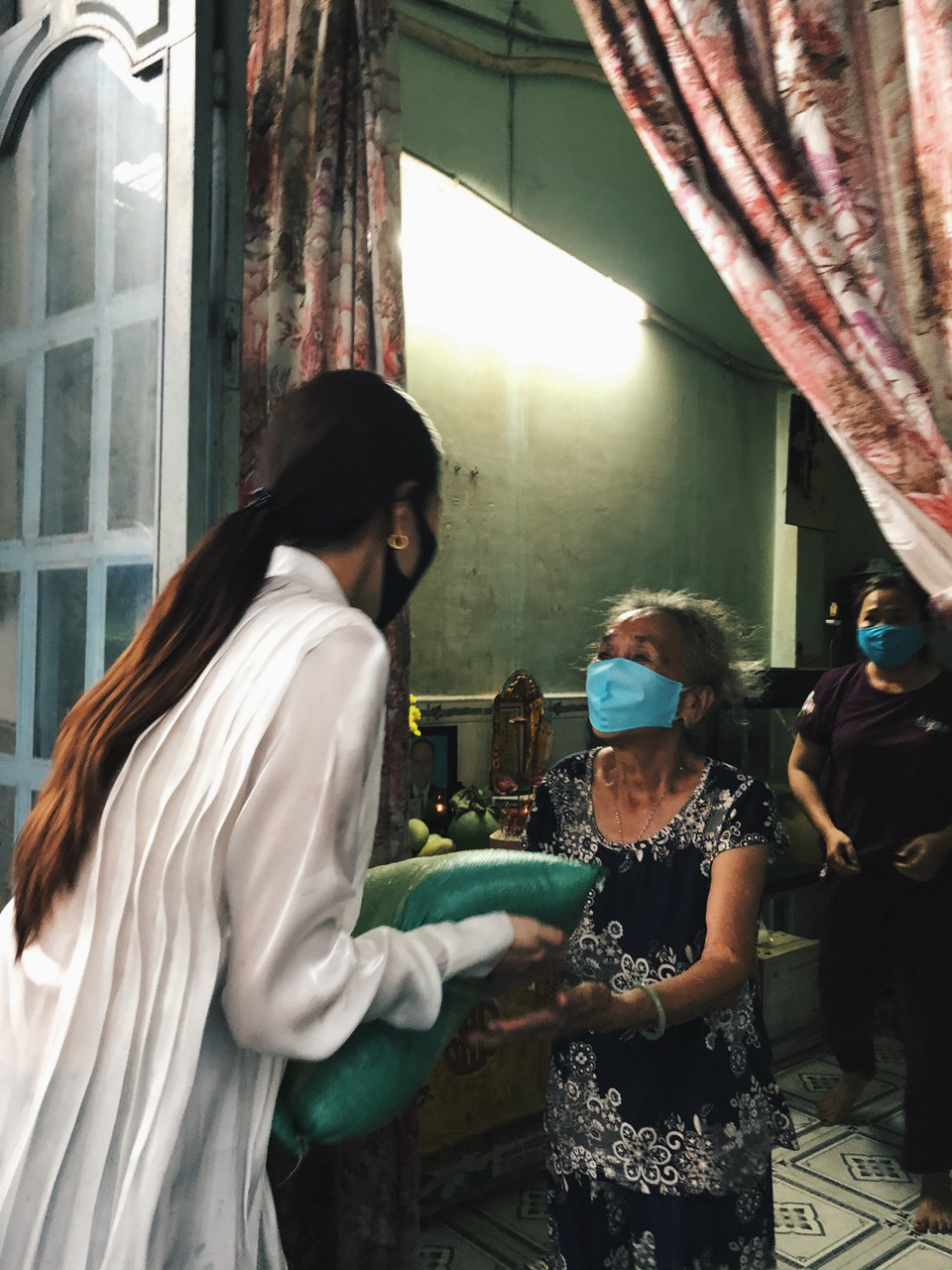 Mặc dù cơn mưa đầu mùa đổ xuống bất ngờ khiến mọi người gặp không ít khó khăn khi di chuyển nhưng khi trao tận tay quà cho các hộ dân, Hoa hậu Khánh Vân cảm thấy vui và ý nghĩa hơn. (Ảnh: CTV/Vietnam+)