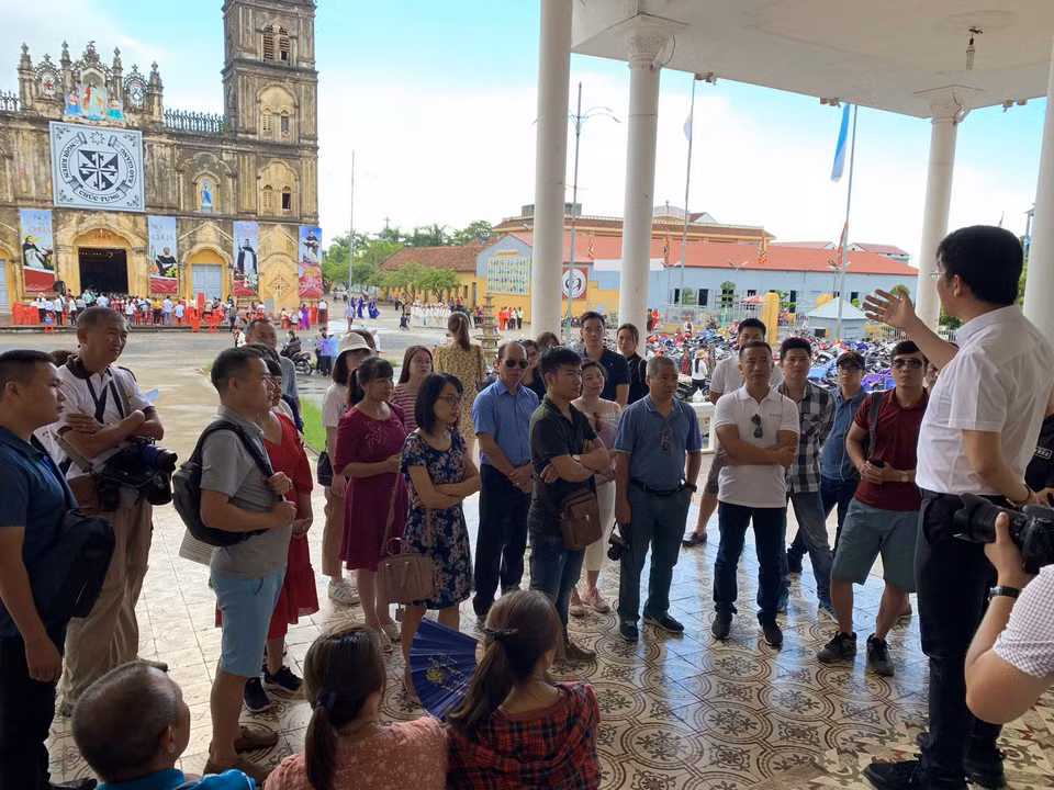 Du khách nghe giới thiệu về nhà thờ cũng như ngày lễ thánh nữ Monica và thánh nữ Anê Lê Thị Thành. (Ảnh: Xuân Mai/Vietnam+)