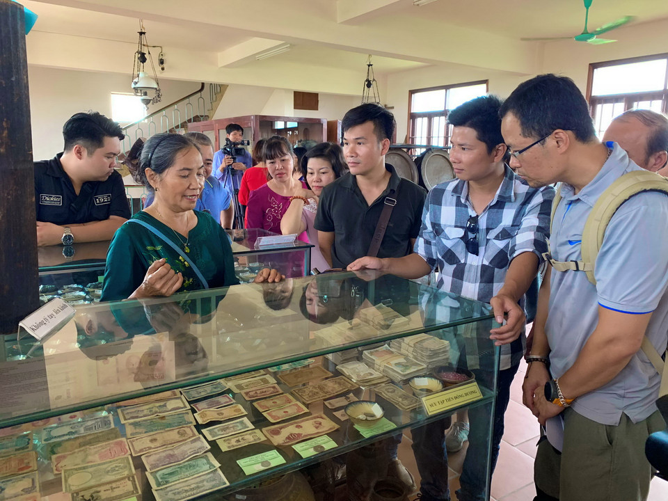 Bà Ngô Thị Kiếu giới thiệu với du khách bộ sưu tập tiền cổ của Việt Nam. (Ảnh: Xuân Mai/Vietnam+)