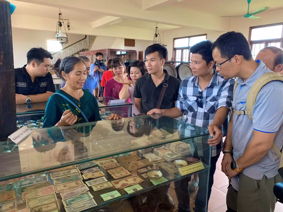 Bà Ngô Thị Kiếu giới thiệu với du khách bộ sưu tập tiền cổ của Việt Nam. (Ảnh: Xuân Mai/Vietnam+)