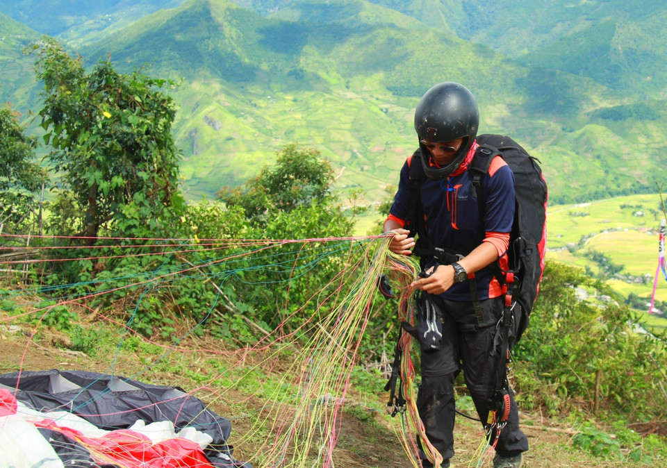 Một phi công kiểm tra dây dù trước khi bay. (Ảnh: Xuân Mai/Vietnam+)