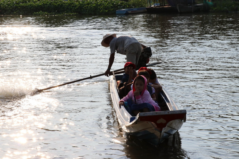 Một ngày hai buổi, các em học sinh Trường Tiểu học Vĩnh Đại (Tân Hưng) được cha mẹ đưa đón bằng xuồng trên quãng đường dài từ 6-8 km. (Ảnh: Bùi Giang/TTXVN)