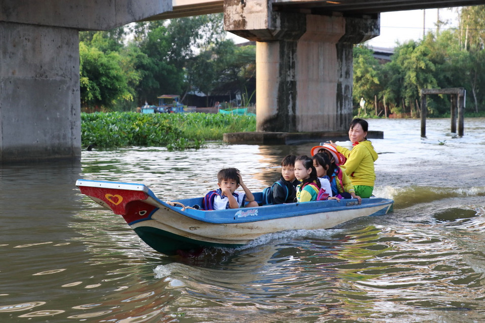 Một ngày hai buổi, các em học sinh Trường Tiểu học Vĩnh Đại (Tân Hưng) được cha mẹ đưa đón bằng xuồng trên quãng đường dài từ 6-8 km. (Ảnh: Bùi Giang/TTXVN)