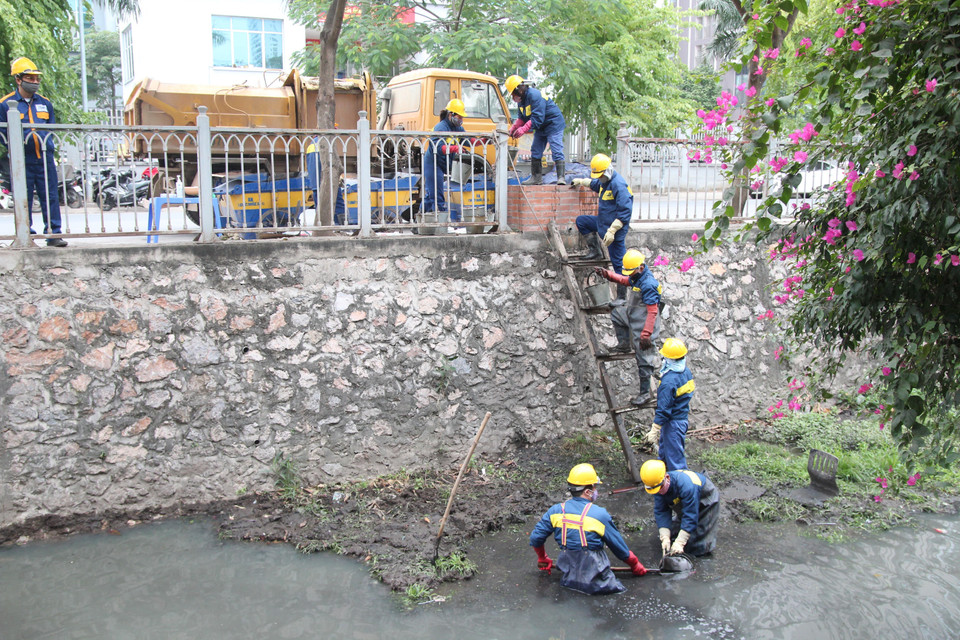 Công nhân Công ty trách nhiệm hữu hạn một thành viên Thoát nước Hà Nội thực hiện nạo vét bùn trên mương trong những ngày giá rét. (Ảnh: TTXVN phát)