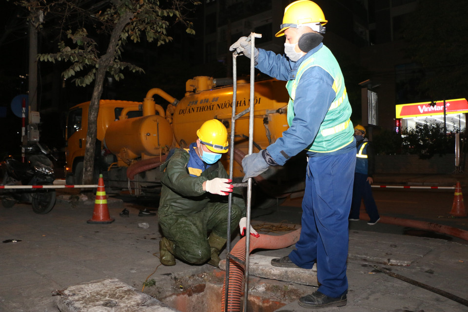 Công ty trách nhiệm hữu hạn một thành viên Thoát nước Hà Nội thực hiện nhiệm vụ chuyên môn trong những ngày nhiệt độ xuống thấp. (Ảnh: Mạnh Khánh/TTXVN)
