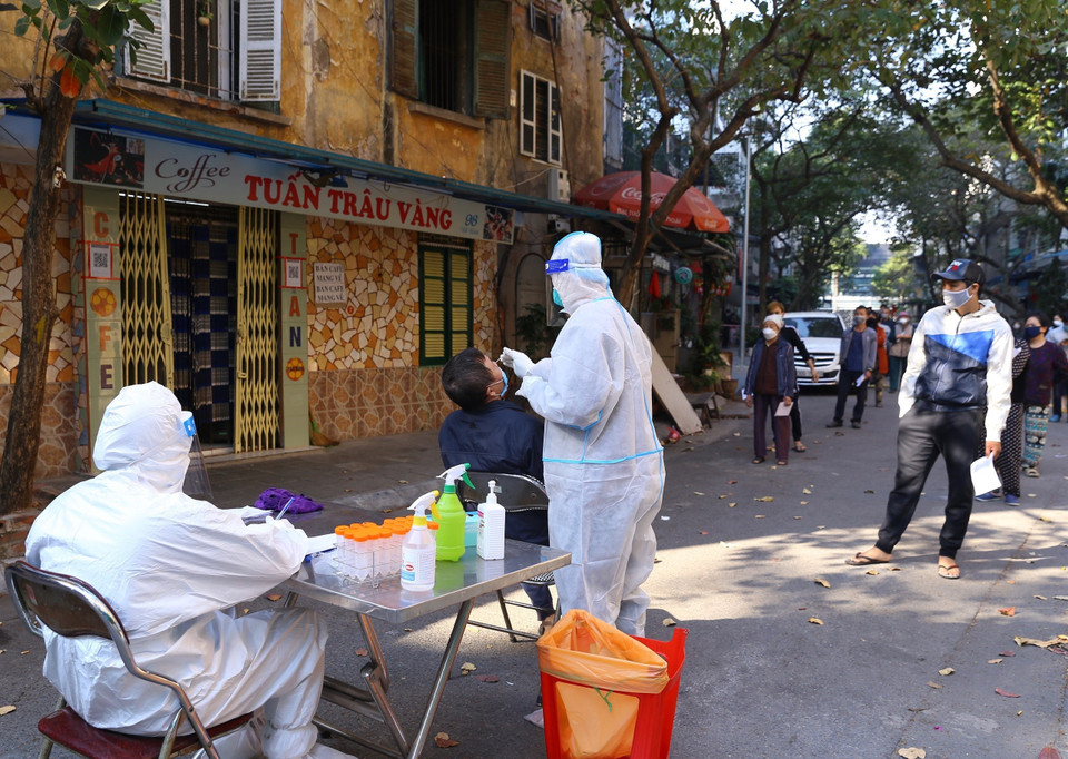 Người dân trong khu vực bị phong tỏa phố Đỗ Hành được lực lượng y tế phường Nguyễn Du lấy mẫu xét nghiệm sàng lọc COVID-19. (Ảnh: Hoàng Hiếu/TTXVN)
