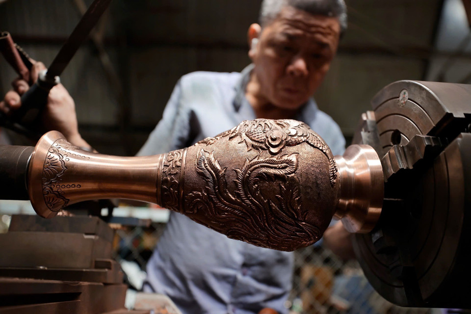 Sản phẩm sau khi đúc xong được người thợ làm bóng, hoàn thiện thủ công qua các công đoạn. (Ảnh: Minh Quyết/TTXVN)